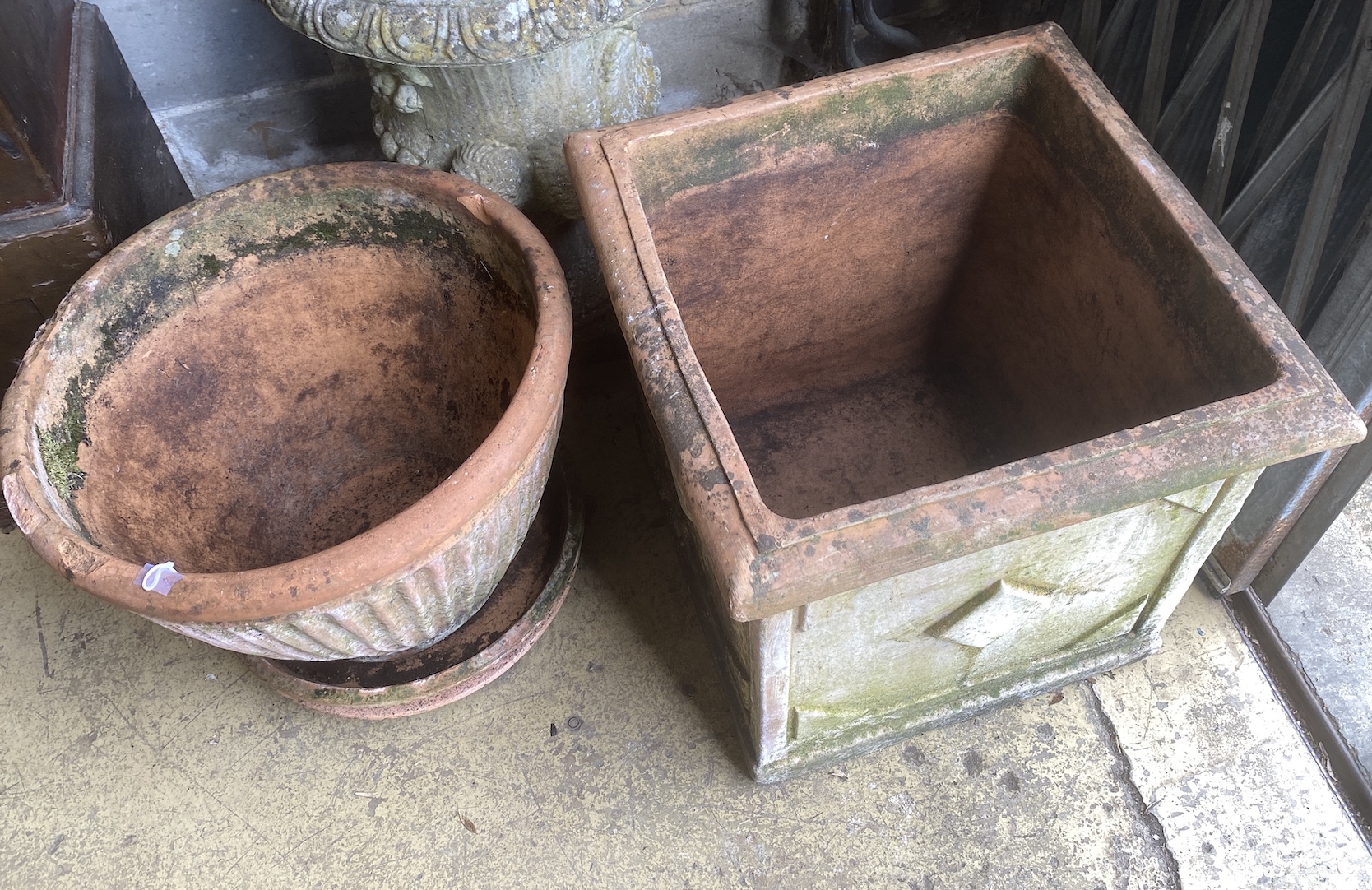 A square weathered terracotta garden planter, width 52cm, height 50cm together with a circular terracotta planter and two circular tray bases